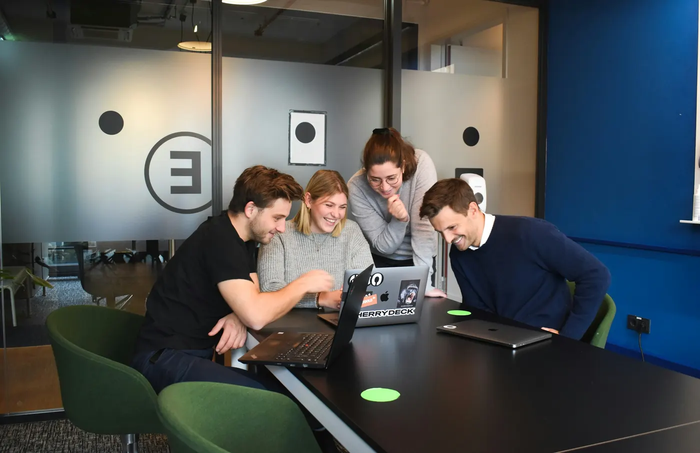 Equipe reunida em torno de um notebook, sorrindo